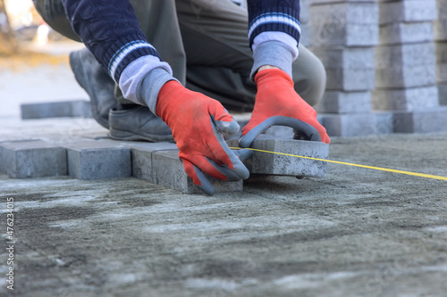 Close-up of construction worker installing laying pavement cement bricks on sidewalk