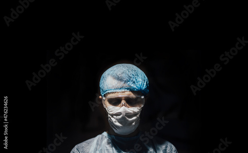 doctor surgeon in uniform in dark operating room, concept of criminal surgery and illegal internal organ transplantation. © velimir