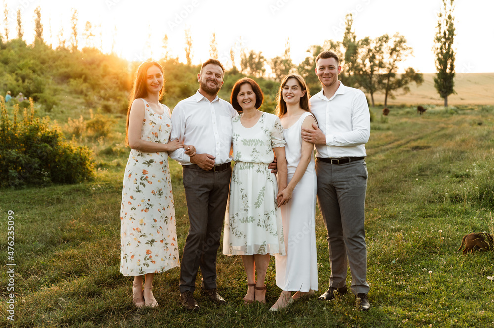 Fototapeta premium portrait of a beautiful family. daughter with mom and son with sister and father together. a group of people of different ages are happy. family walk at sunset day in summer.
