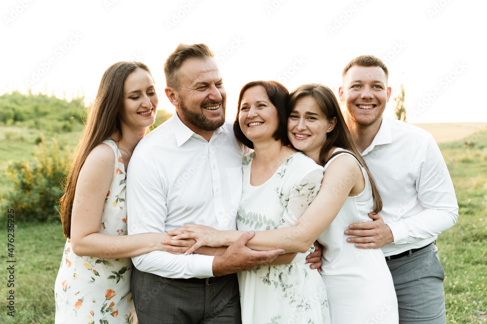 Loving young family hugging and smiling together on the background of nature. portrait of a family of different ages at sunset.