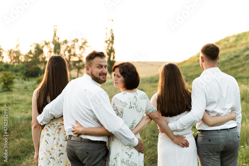 portrait of a beautiful family. daughter with mom and son with sister and father together. a group of people of different ages are happy. family walk at sunset day in summer.