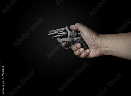 male hand holding a black revolver on a black background Criminals with handguns at close range Weapons for attack or defense © pornchai