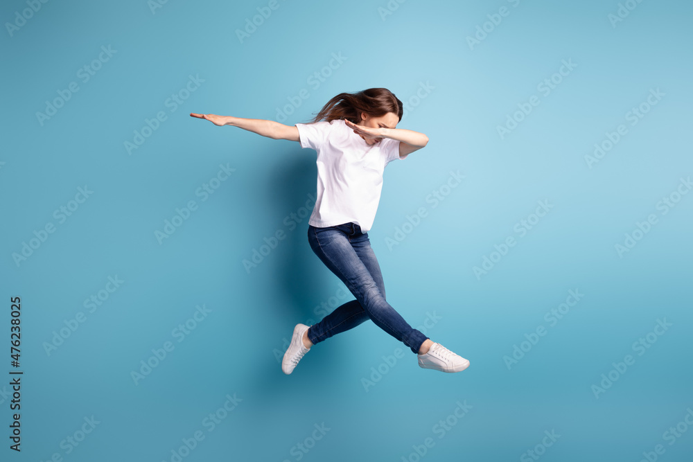 Full body photo of young attarctive girl jump up dance dab chill isolated over blue color background Full body photo of young attarctive girl jump up dance dab chill isolated over blue color background