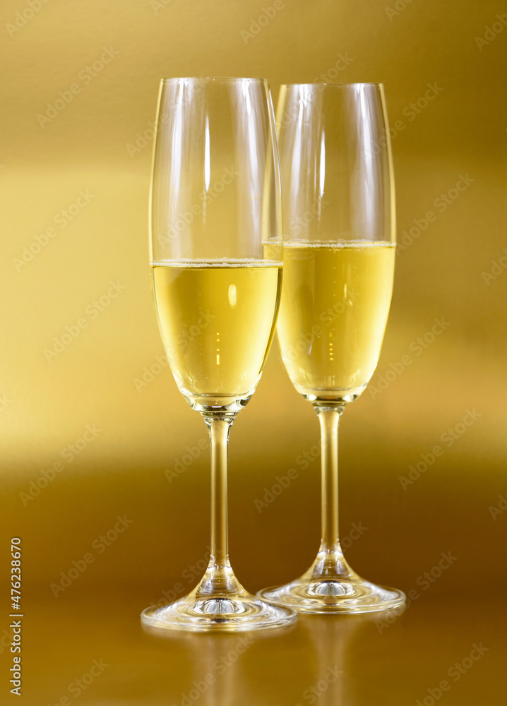 Two glasses of champagne on a golden background stock images. Sparkling wine isolated on a gold shiny background vertical stock photo. Celebration drink images