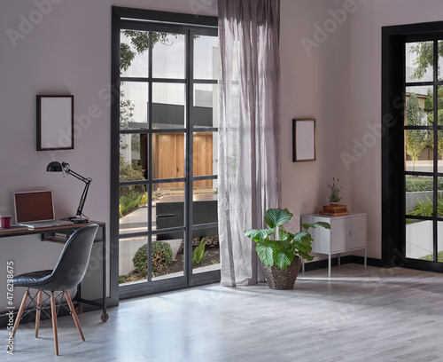Modern rom with working table and armchair style  parquet floor  frame lamp decor  curtain  garden view house interior.