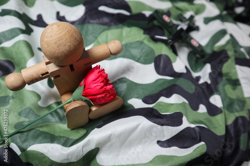 red flowerand wooden dummy with camouflage color design for love and passion of military concept photo