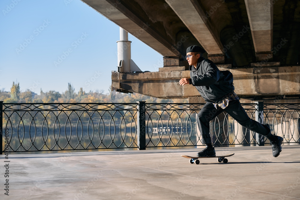 Obraz premium Skater rides on skateboard at empty concrete embankment on the urban background