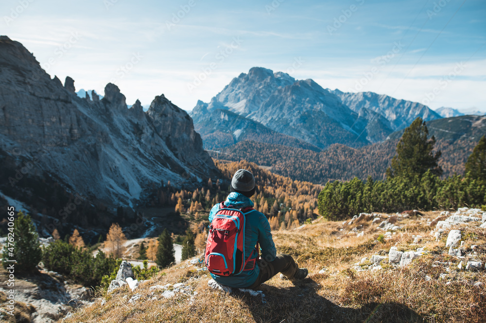 Young man standing on a top of the mountains with the beautiful view. Autumn Dolomites in the Italy. 