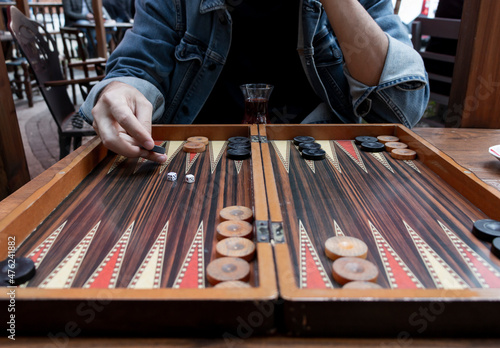 Fototapeta Close up man hand holding backgammon checker and playing backgammon at outside