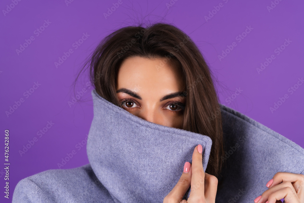 Young woman in a gray coat on a purple background posing, cozy and warm, autumn winter style Young woman in a gray coat on a purple background posing, cozy and warm, autumn winter style