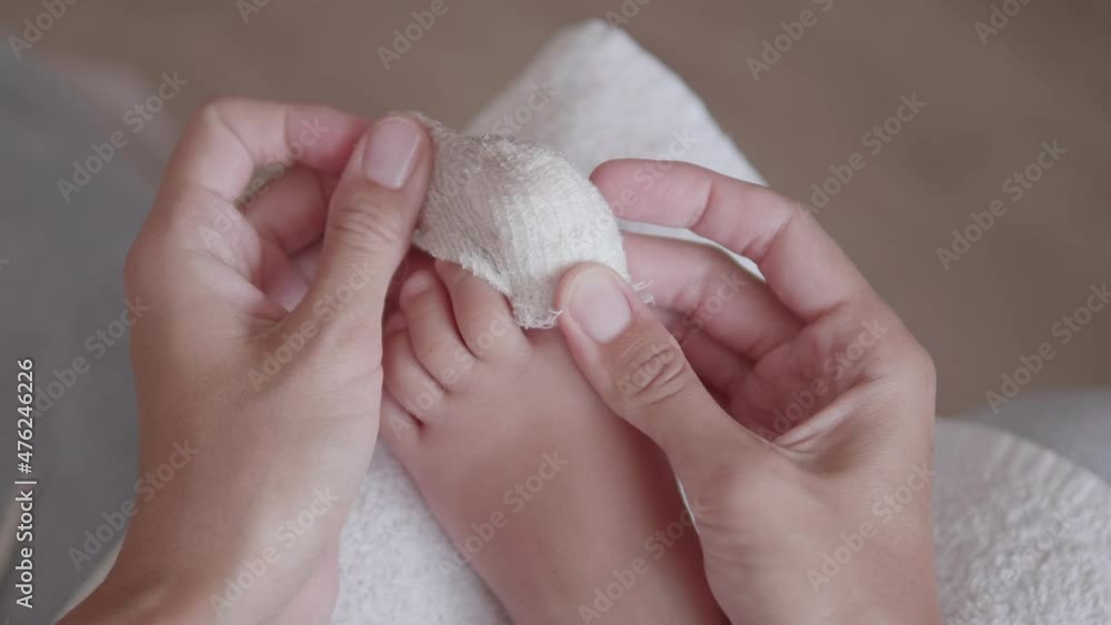 Mother bandages her child's big toe. Closeup photo of kid's foot with