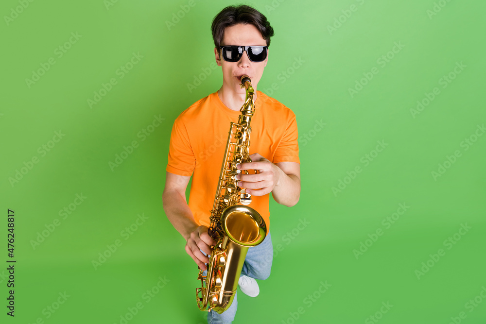 Fototapeta premium Photo of cool charming young man hold hands play sax wear sunglass hobby isolated on green color background