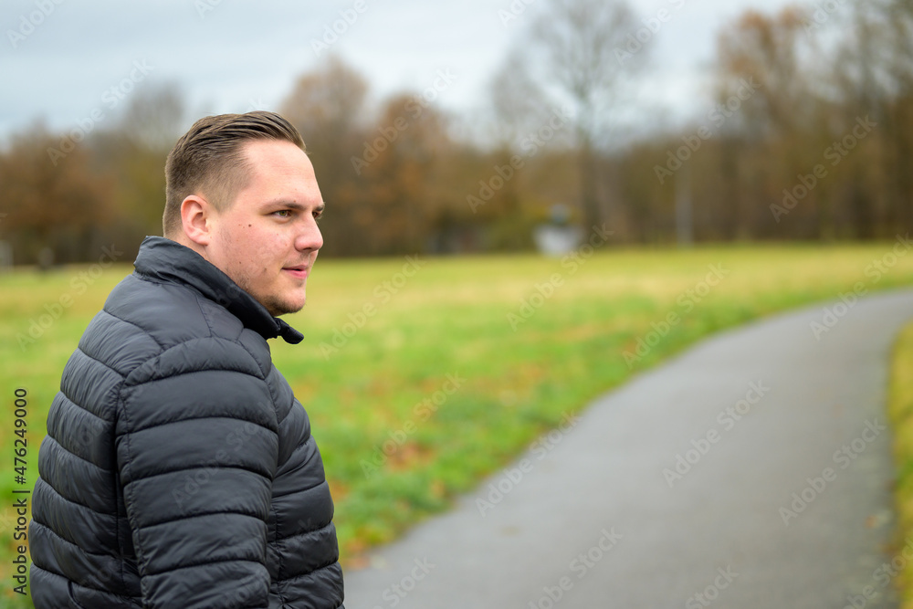Young man turning back as he walks along a rural road