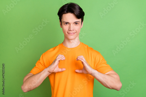 Photo of young happy positive man hold hands camera imagine good mood isolated on green color background photo