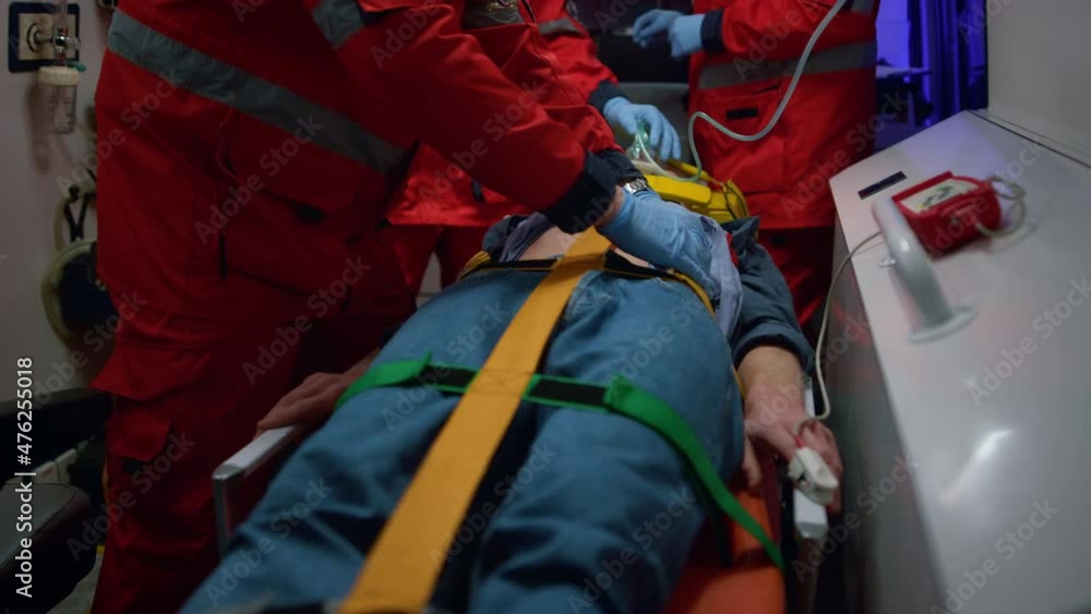 Paramedics giving first aid to patient in ambulance car. Doctor examining man Paramedics giving first aid to patient in ambulance car. Doctor examining man