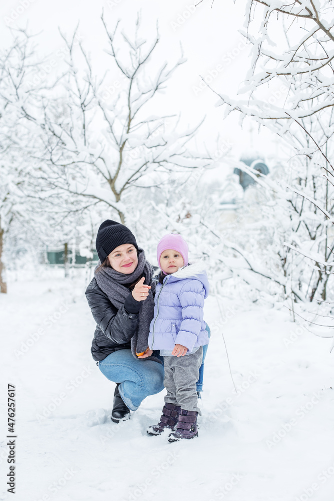 Happy mom and child spend time together and play. Walk in the snowy park. Happy mom and child spend time together and play. Walk in the snowy park.