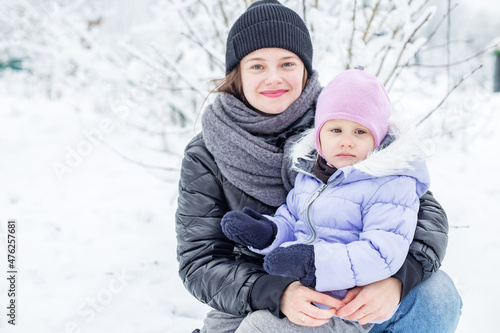 Happy mom and child spend time together and play. Walk in the snowy park.