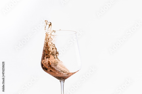 Glass of splashing alcohol on a light background