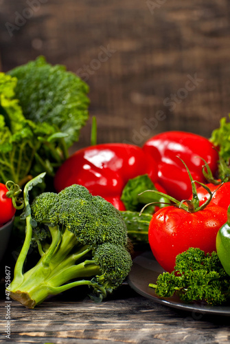 Cabbage, peppers, tomatoes, cucumbers, lettuce, cherry tomatoes, broccoli, arugula on a black background. variety of vegetables on a pile on a wooden table.