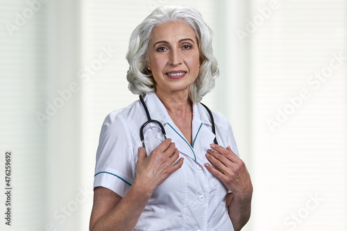 Pretty senior woman doctor with stethoscope looking at camera.