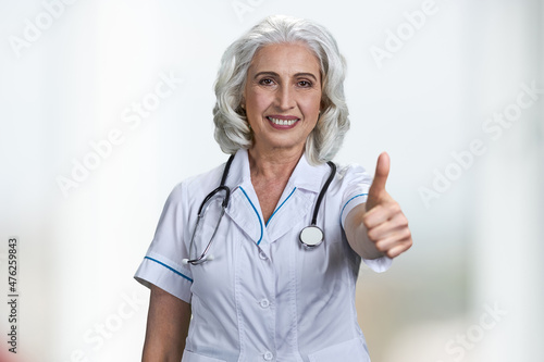 Successful senior woman doctor gesturing thumb up to camera.