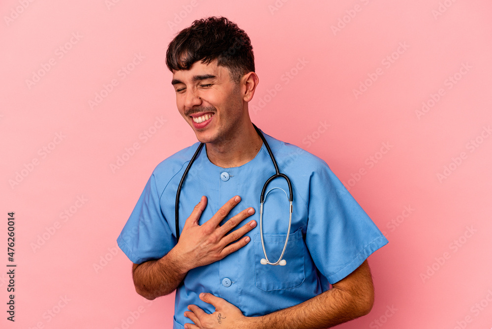 Young mixed race nurse man isolated on pink background laughing and having fun. Young mixed race nurse man isolated on pink background laughing and having fun.