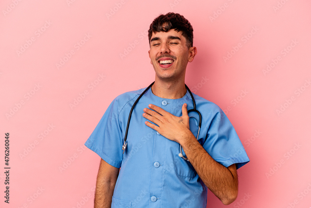 Young mixed race nurse man isolated on pink background laughs out loudly keeping hand on chest. Young mixed race nurse man isolated on pink background laughs out loudly keeping hand on chest.