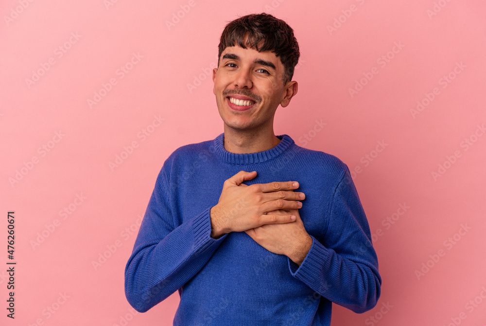 Young mixed race man isolated on pink background has friendly expression, pressing palm to chest. Love concept. Young mixed race man isolated on pink background has friendly expression, pressing palm to chest. Love concept.