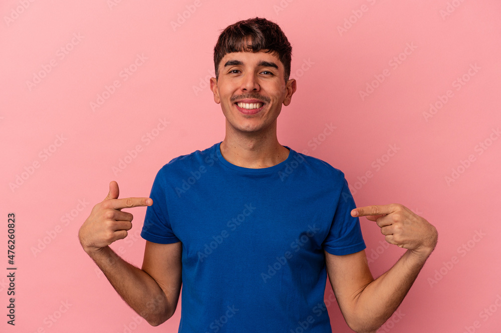 Young mixed race man isolated on pink background points down with fingers, positive feeling.