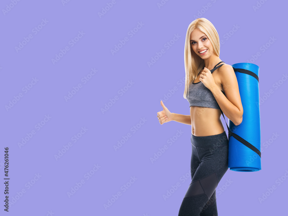 Young cheerful smiling blond woman in sportswear with fitness or yoga mat, showing thumb up, isolated over violet purple background. Ready for fit exercising concept. Young cheerful smiling blond woman in sportswear with fitness or yoga mat, showing thumb up, isolated over violet purple background. Ready for fit exercising concept.
