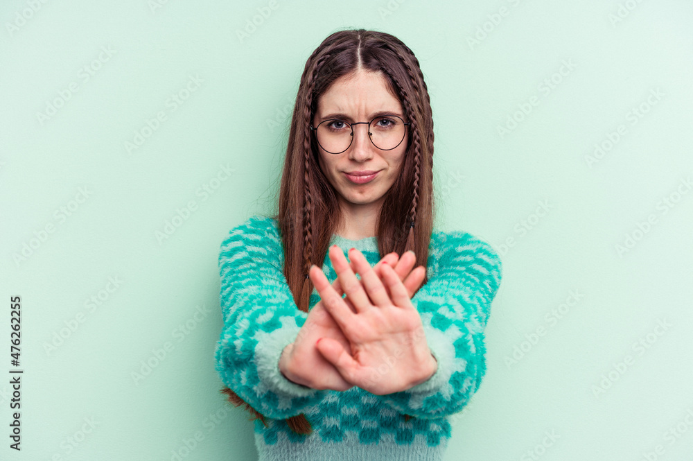 Young caucasian woman isolated on green background standing with outstretched hand showing stop sign, preventing you. Young caucasian woman isolated on green background standing with outstretched hand showing stop sign, preventing you.