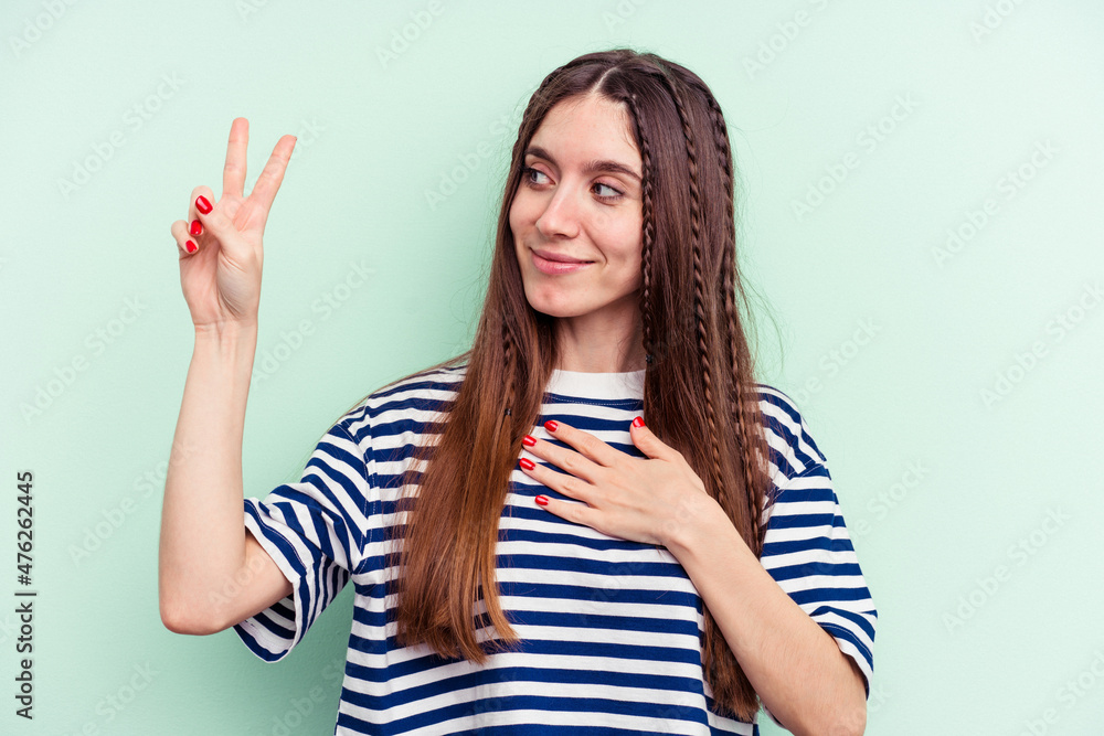Young caucasian woman isolated on green background taking an oath, putting hand on chest. Young caucasian woman isolated on green background taking an oath, putting hand on chest.