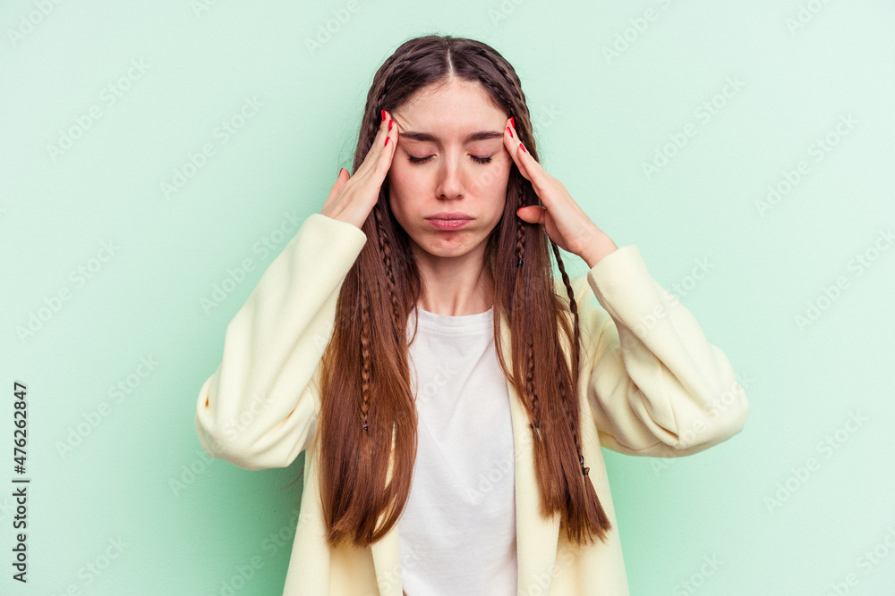 Young caucasian woman isolated on green background having a head ache, touching front of the face. Young caucasian woman isolated on green background having a head ache, touching front of the face.