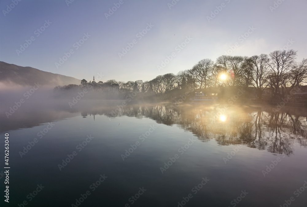 fog in lake pamvotis of ioannina city greece in winter morning sunrise among leafless  trees