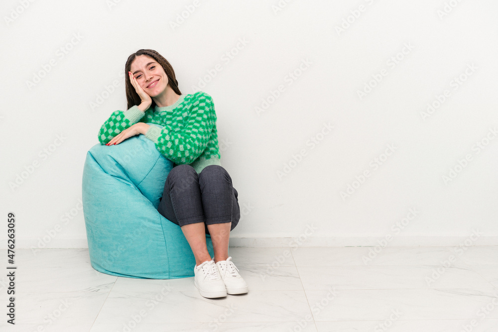 Young caucasian woman sitting on a puff isolated on white background Young caucasian woman sitting on a puff isolated on white background