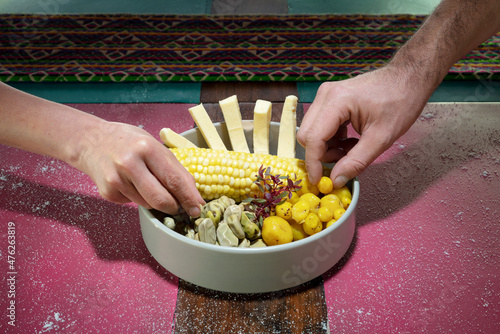 hands eating from a plate of corn, beans, cheese and mellocos, one is a man and the other a woman. (typical ecuadorian food) (choclo con queso). photo