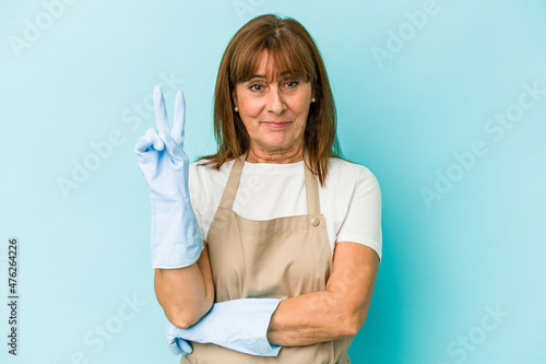 Middle age caucasian woman cleaning home isolated on blue background showing number two with fingers.