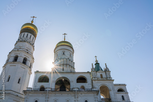 Ivan the Great Bell Tower, with Assumption Belfry on the right in Moscow Kremlin. Blue sky background with sunbeams
