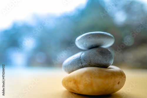 Three Zen rocks stacked on the warm-colored promenade on blue bokeh forest background