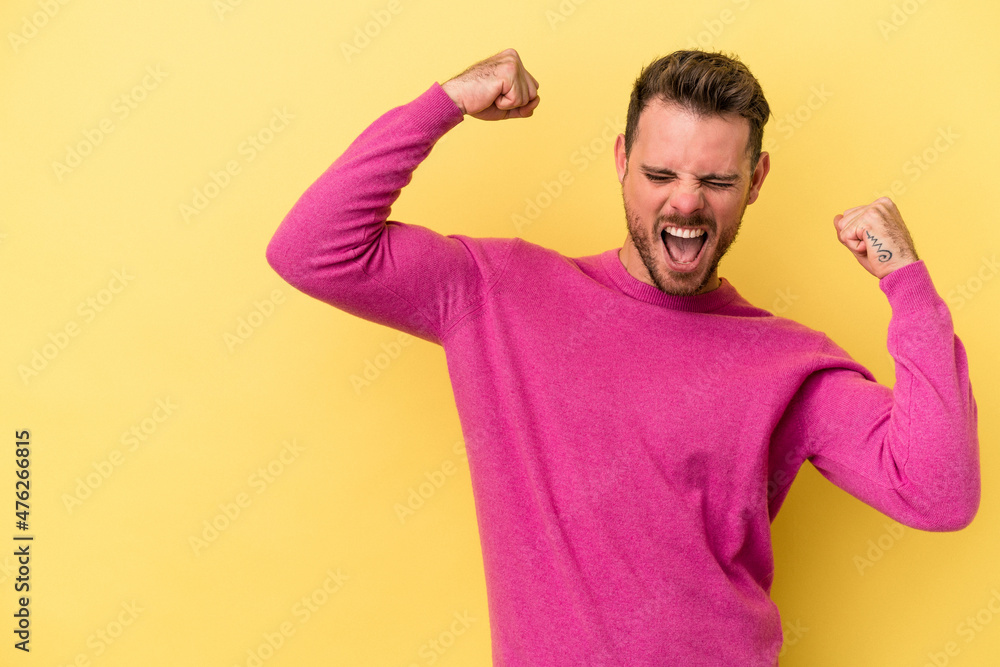 Young caucasian man isolated on yellow background raising fist after a victory, winner concept. Young caucasian man isolated on yellow background raising fist after a victory, winner concept.