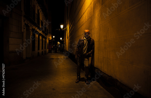 Adult man on street against brick wall with light of street lamp at night. Shot in Madrid  Spain