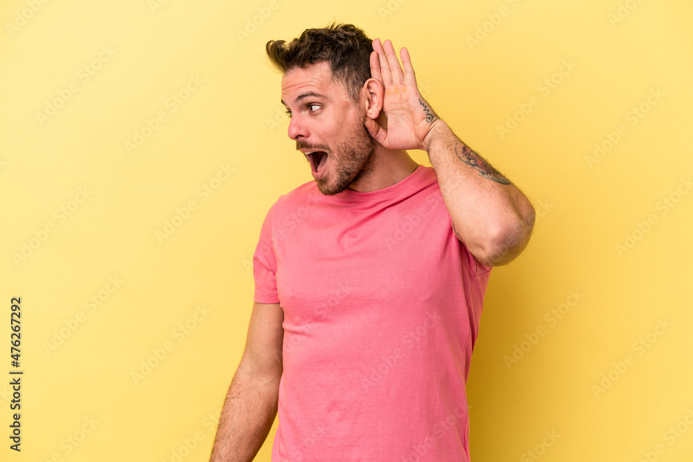 Young caucasian man isolated on yellow background trying to listening a gossip. Young caucasian man isolated on yellow background trying to listening a gossip.