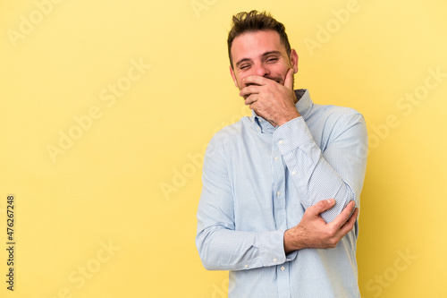Young caucasian man isolated on yellow background laughing happy, carefree, natural emotion.
