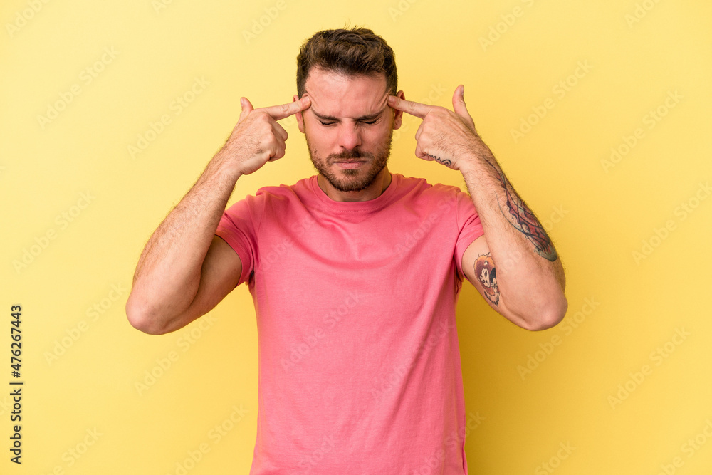 Young caucasian man isolated on yellow background focused on a task, keeping forefingers pointing head. Young caucasian man isolated on yellow background focused on a task, keeping forefingers pointing head.