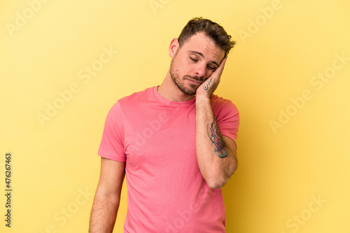 Young caucasian man isolated on yellow background who is bored  fatigued and need a relax day.
