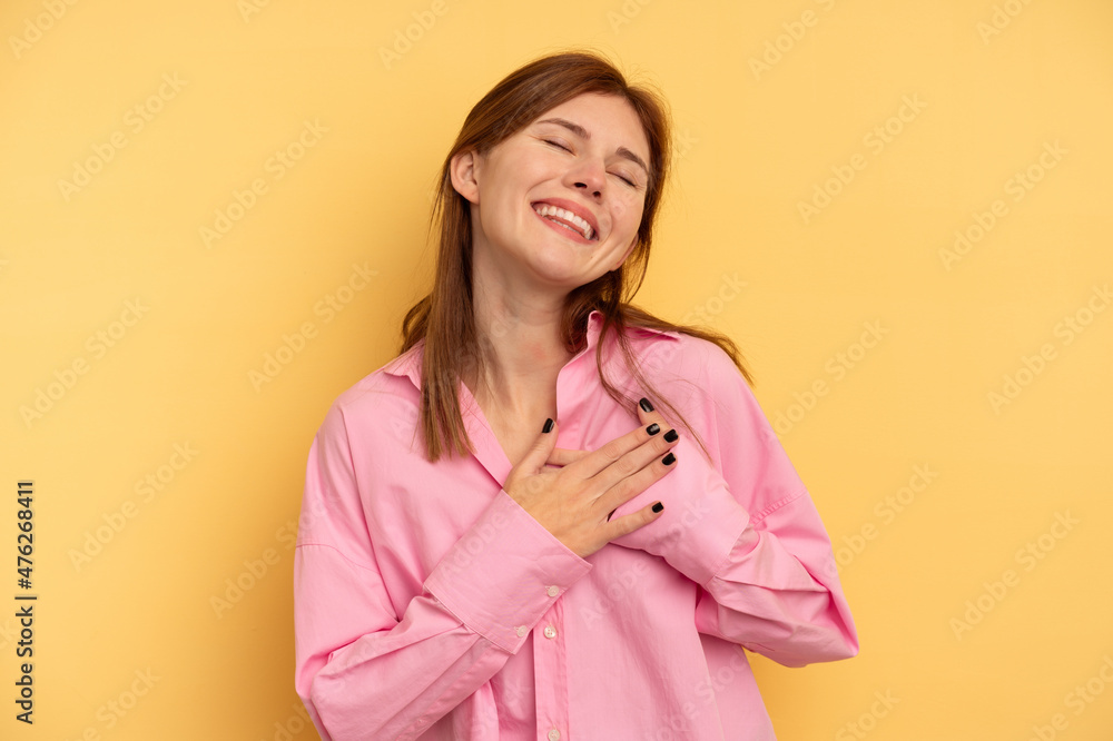 Young English woman isolated on yellow background has friendly expression, pressing palm to chest. Love concept. Young English woman isolated on yellow background has friendly expression, pressing palm to chest. Love concept.