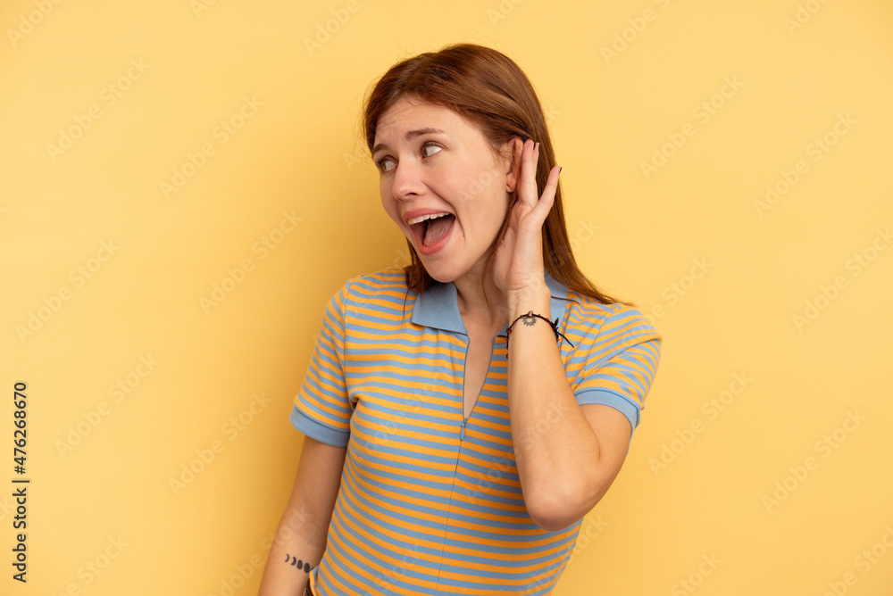 Young English woman isolated on yellow background trying to listening a gossip. Young English woman isolated on yellow background trying to listening a gossip.