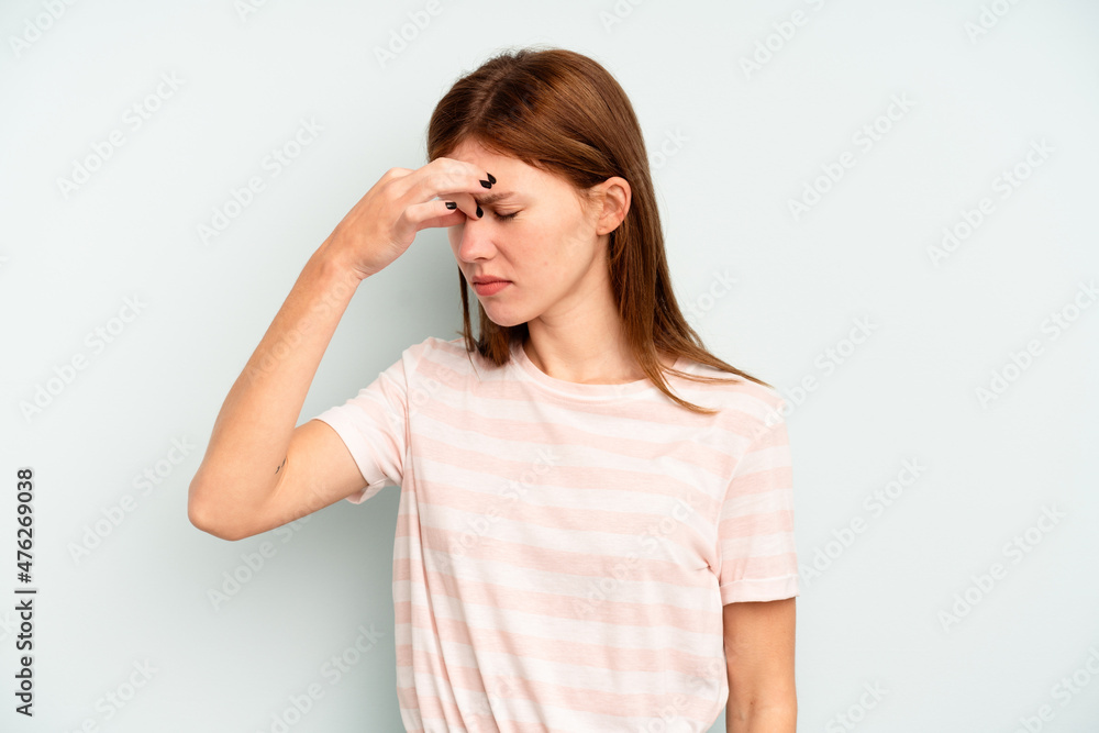 Young English woman isolated on blue background having a head ache, touching front of the face. Young English woman isolated on blue background having a head ache, touching front of the face.