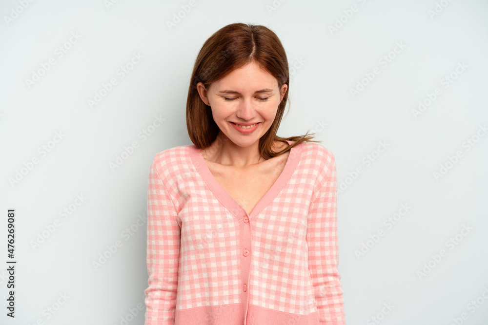 Young English woman isolated on blue background laughs and closes eyes, feels relaxed and happy. Young English woman isolated on blue background laughs and closes eyes, feels relaxed and happy.