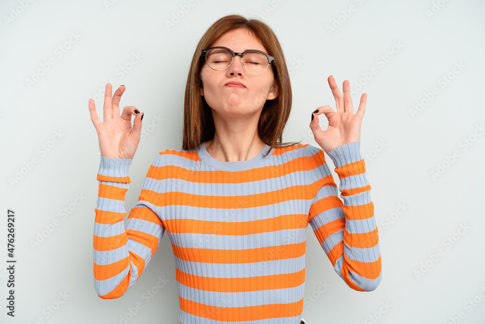 Young English woman isolated on blue background relaxes after hard working day, she is performing yoga. Young English woman isolated on blue background relaxes after hard working day, she is performing yoga.